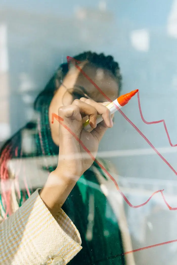 about-us-01 A businesswoman draws a red financial graph on a glass panel, symbolizing strategy and success.
